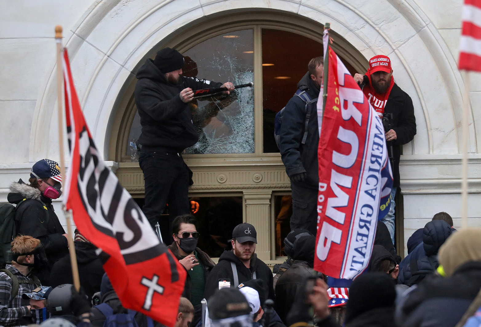 A man breaks a window as a mob of supporters of former US president Donald Trump storm the US Capitol Building in Washington